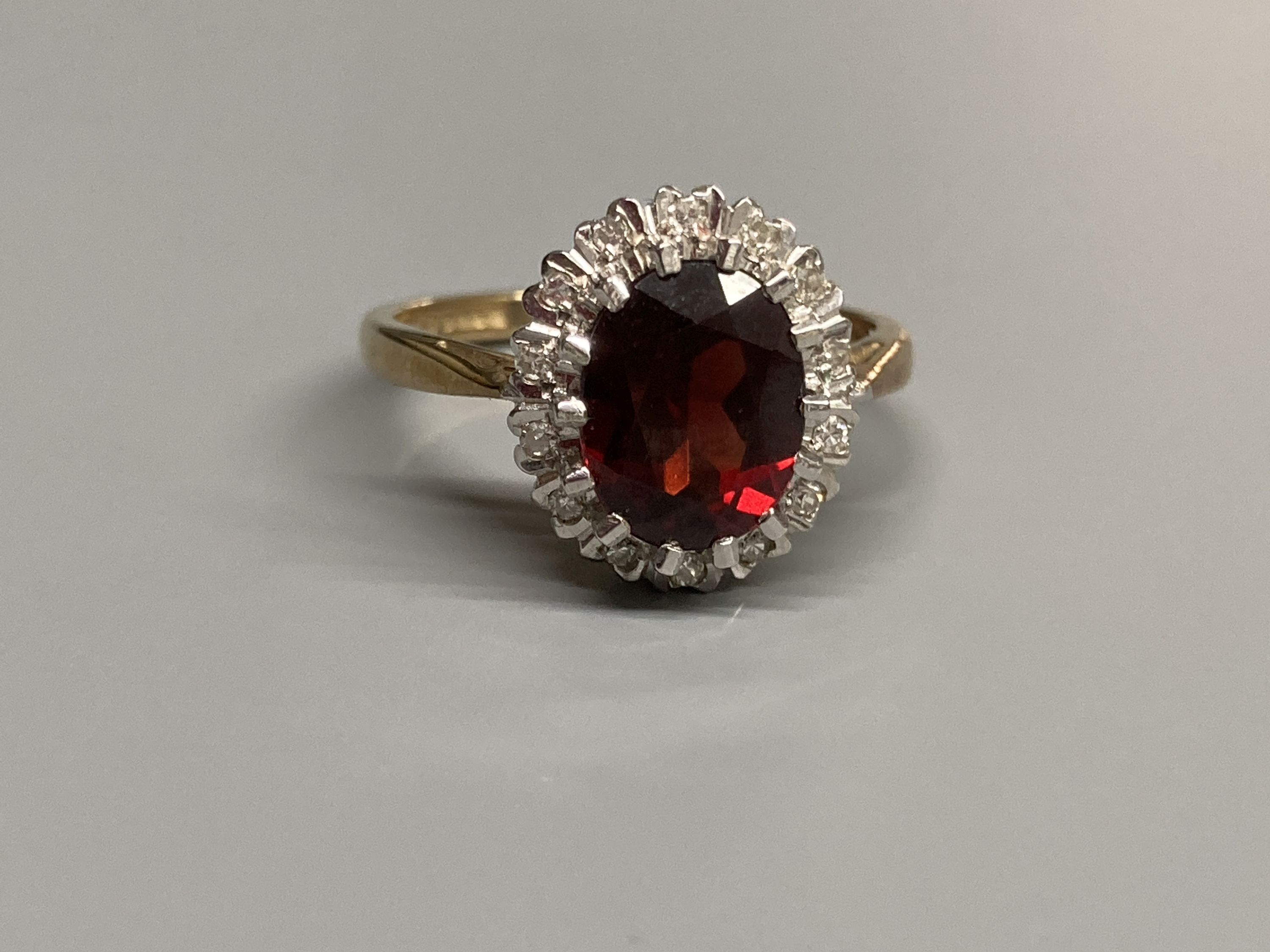 A modern 9ct gold, garnet and diamond set oval cluster ring, size N, gross 3.4 grams.